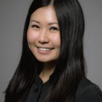 A portrait of a woman smiling with a gray background.