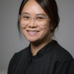 A portrait of a woman smiling with a gray background.